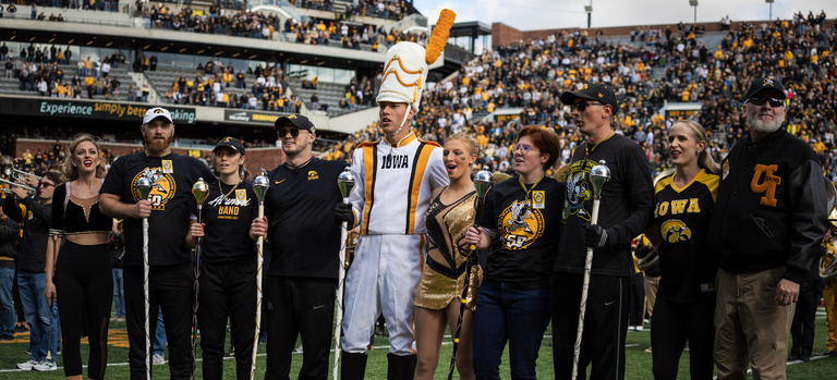 HMB alumni drum majors and Golden Girls with Christian Frankl and Ella McDaniel, singing Alma Mater Iowa on the field in Kinnick Stadium during Pregame at Homecoming